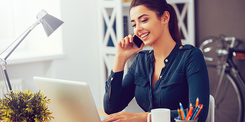 Stock photo of woman on phone in front of computer