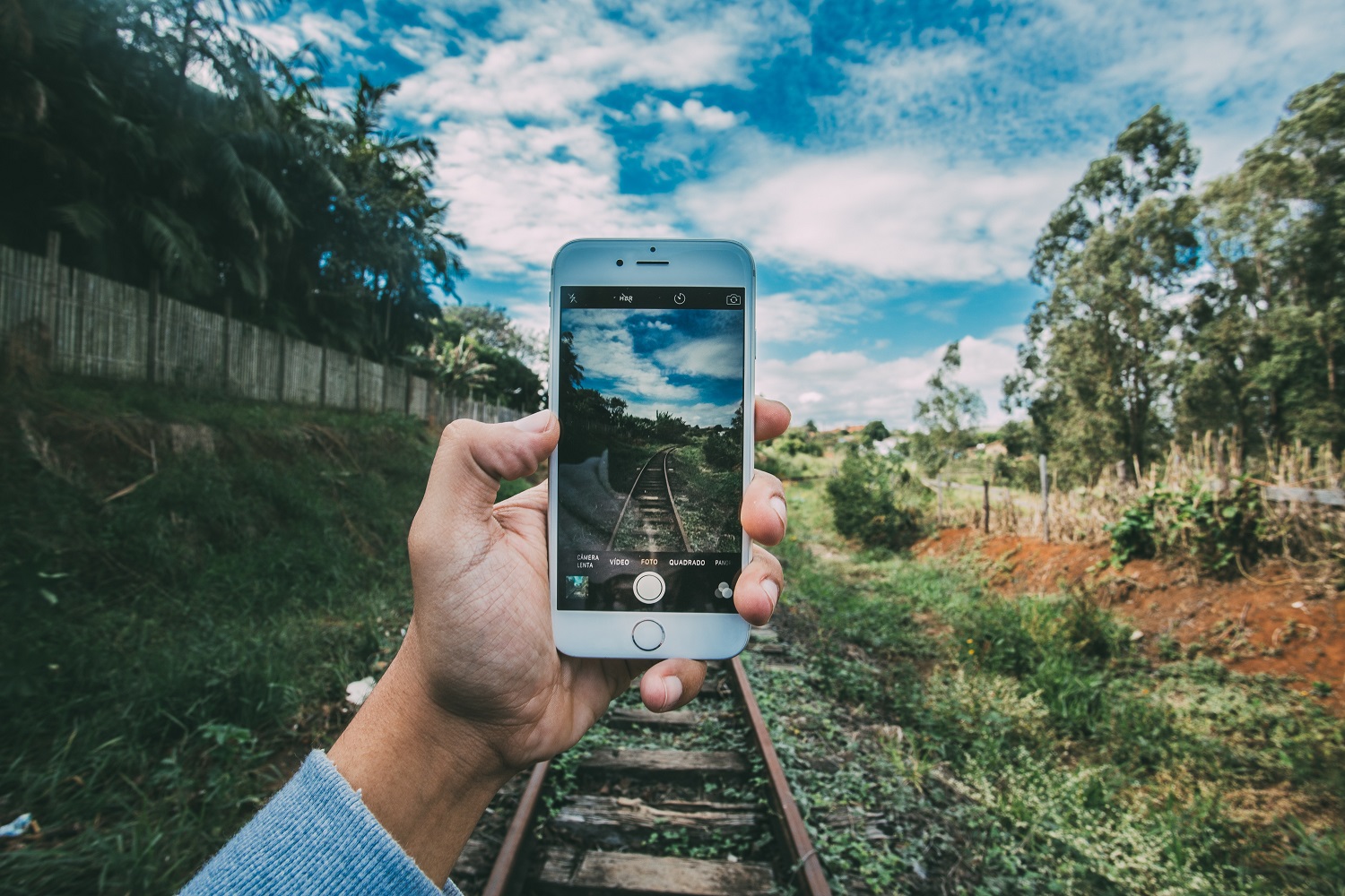 Hand taking photo on a phone camera in front of train tracks - Continuing Education at Seattle Central College 