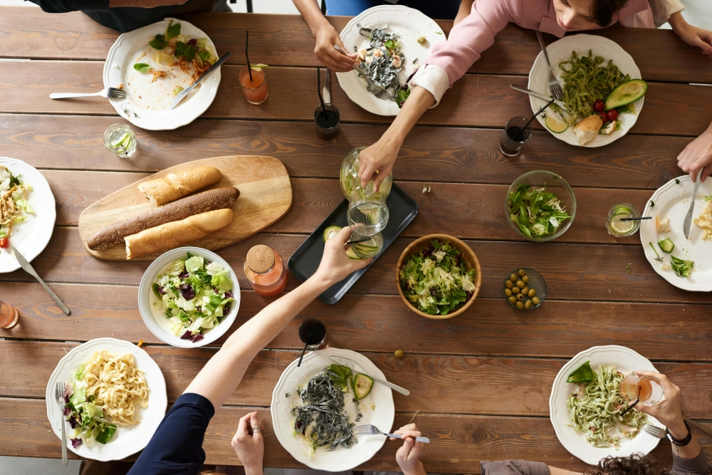 Overhead view of dinner table with multiple dishes and people  