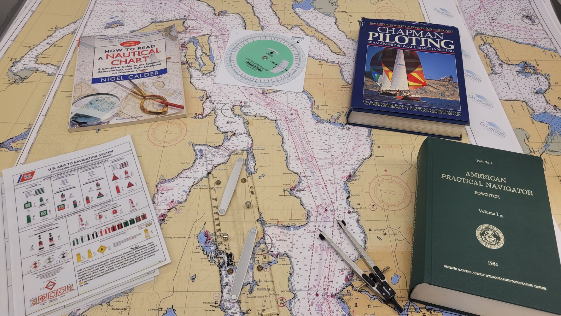 Boating map with various boating guide books and tools spread out on a flat surface. 