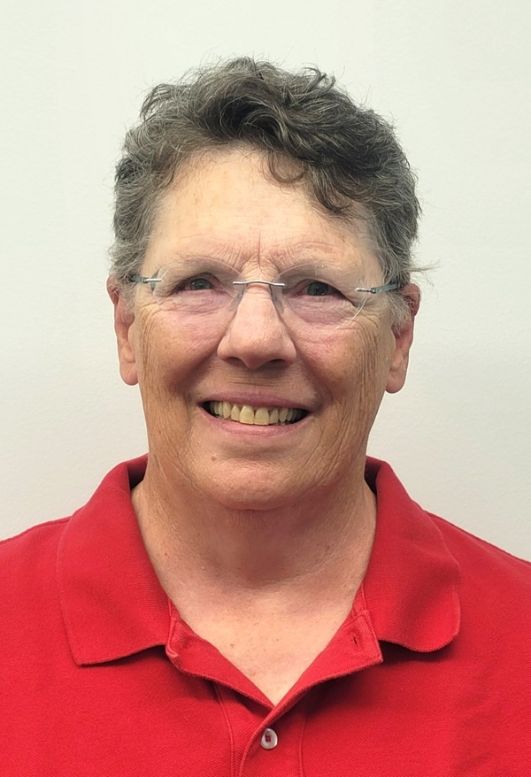 Head shot of woman smiling with short dark hair with glasses wearing red shirt. 