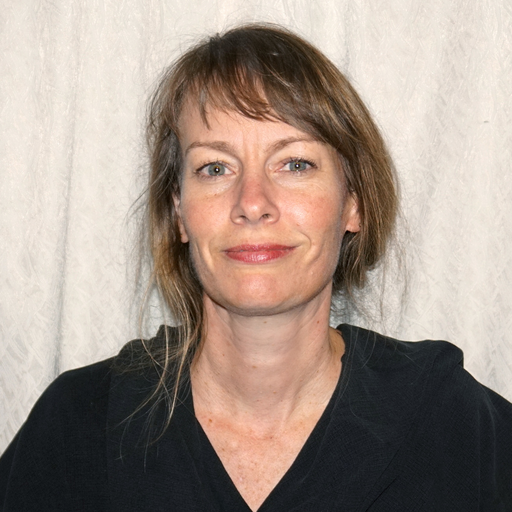Headshot of smiling woman with fair skin and medium length brown hair pulled back. 
