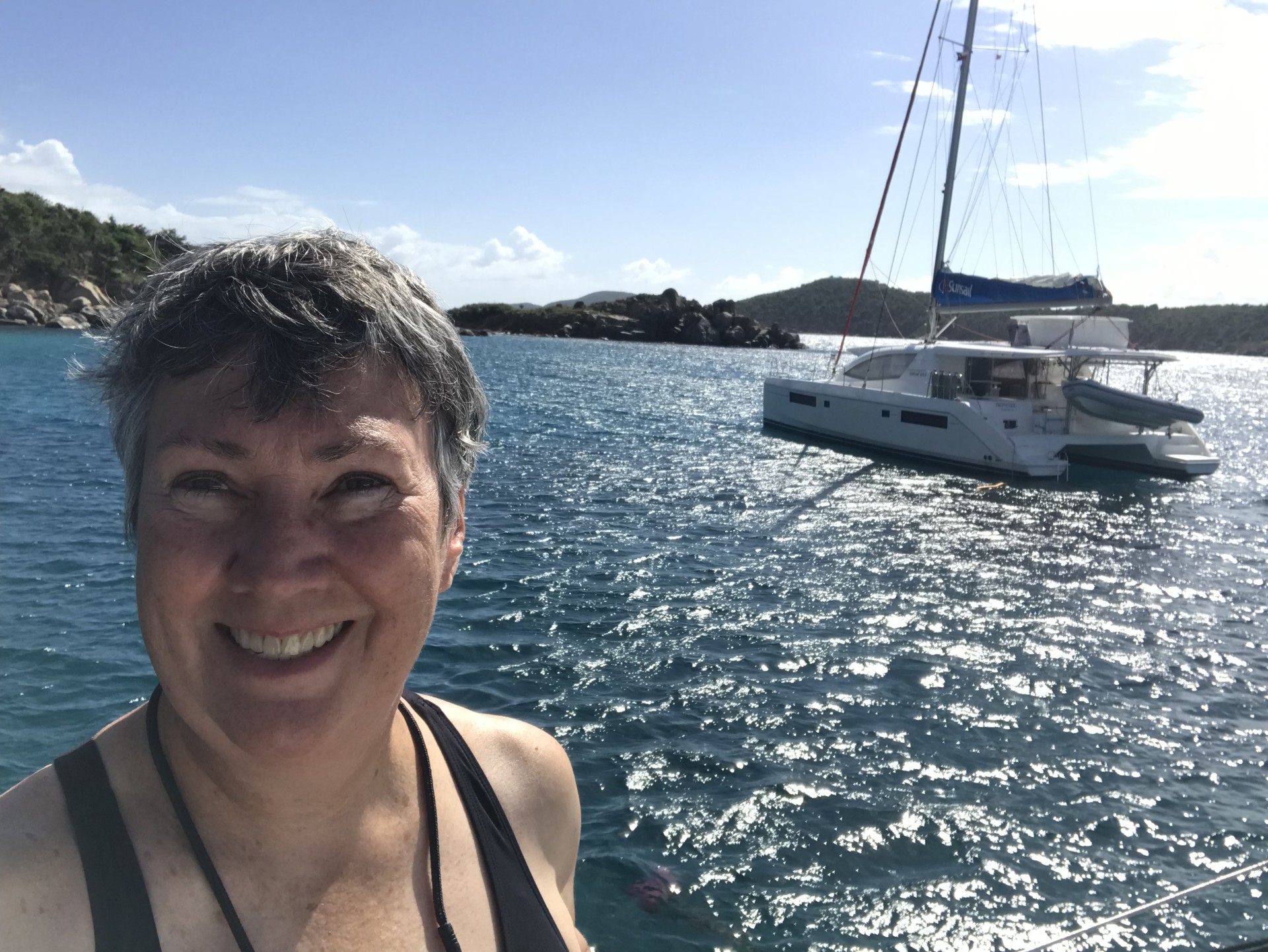 Instructor Margaret Pommert smiles with water and sailboat behind her. 