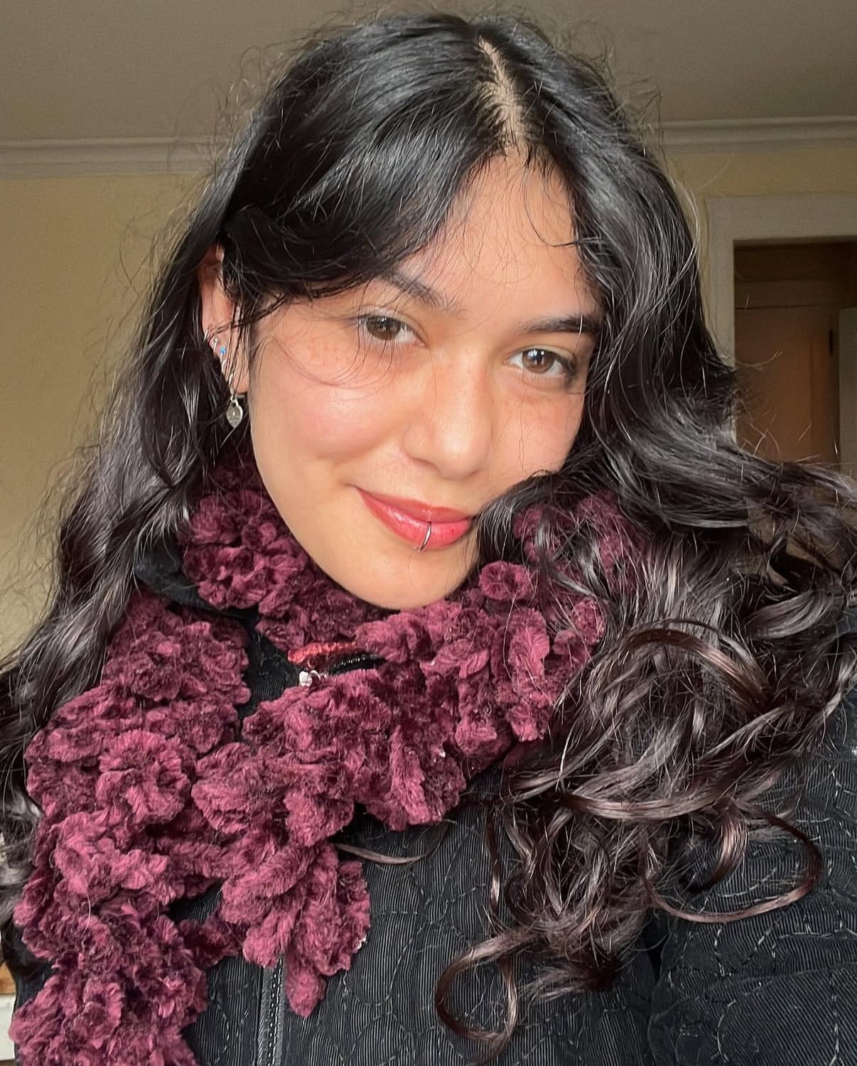 Photo of woman with long dark hair wearing lipstick and textured maroon scarf.  