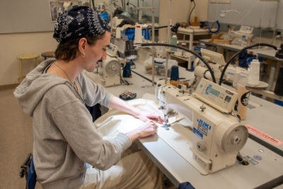 Student sews at industrial machine in classroom at Seattle Central's Apparel Design & Development department.